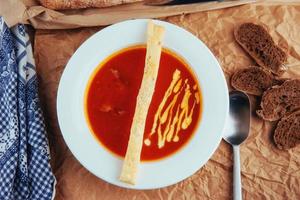 Fresh tomato soup in a white mask with bread baguette photo