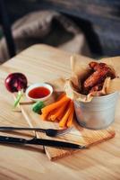 alitas de pollo adornadas con salsa y verduras sobre mesa de madera