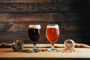 Two glasses of beer on a wooden table grains photo
