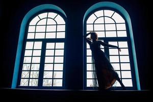 mujer con vestido vintage en el interior junto a la ventana foto