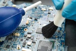 Technician use brush and air blower ball to clean dust in circuit board computer. Repair upgrade and maintenance technology. photo