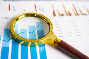 Magnifying glass on charts graphs paper. Financial development, Banking Account, Statistics, Investment Analytic research data economy, Stock exchange trading, Business office company meeting concept. photo