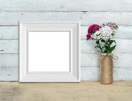 Square Vintage White Wooden Frame mockup near a bouquet of sweet-william  stands on a wooden table on a painted white wooden background. Rustic style, simple beauty. 3d render. photo