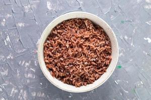 arroz rojo en un tazón aislado sobre fondo gris comida asiática cocinada. foto