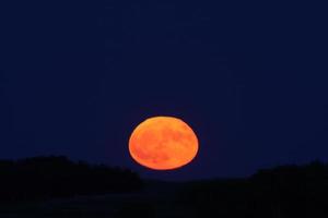 luna llena saliendo sobre las colinas foto