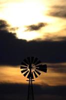 Old windmill generator against darkened sky photo