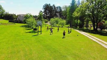 Aerial view group of young caucasian friends enjoy playing volleyball on grassy area in Lithuania countryside video