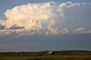 Thunderhead forming over an old Saskatchewan farm house photo