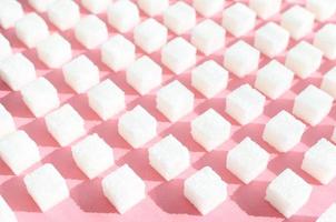 Refined sugar on pink background.Cubes of sweet and white sugar in geometricshape. Hard shadows. photo