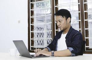 Young Asian man shocked and wow what he see in the laptop when in call on smartphone photo