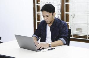 joven asiático sorprendido y asombrado por lo que ve en la computadora portátil. foto