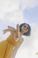 retrato de una mujer asiática feliz y sonriente con vistas al cielo azul desde abajo. foto