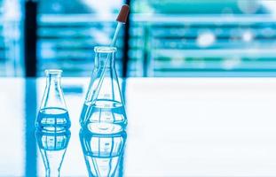 Chemistry experiment concept in science laboratory Two science flasks of different sizes contain different chemicals on white desk. nobody. Copy space on right for design. Blurred background. Close up photo