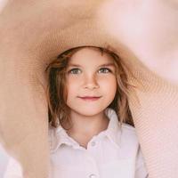 Adorable cheerful little girl in straw hat at home indoor. Fashion, style, childhood, emotions, growing up concept photo