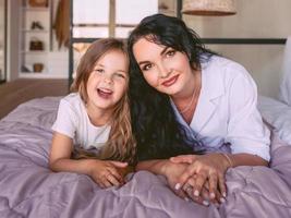 cheerful and beautiful mother and daughter together in the bedroom. Interior, family, love, support, mom and daughter concept. photo