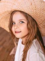 Adorable cheerful little girl in straw hat at home indoor. Fashion, style, childhood, emotions, growing up concept