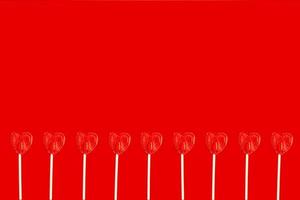 various heart shaped lollipops side by side on a red background with copy space photo