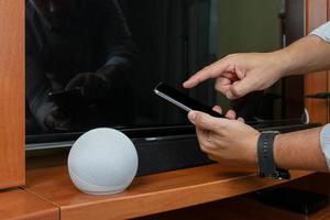 Crop man using smart speaker at home photo