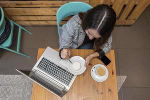 mujer comiendo postre y bebiendo café durante el trabajo en línea foto