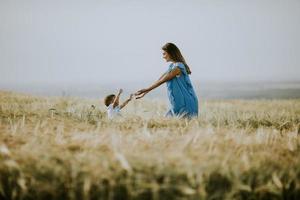 joven madre embarazada con su lindo niño en el campo en un hermoso día soleado foto