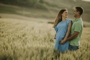 joven esposo y su esposa embarazada en el campo de verano foto