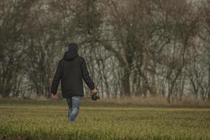 un hombre con una cámara camina por el campo foto