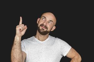 Portrait Of white bald man with beard in white t-shirt smiling and showing thumb up. isolate on a black background photo