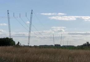 Postes de electricidad de alta tensión cruzando tierras de cultivo foto