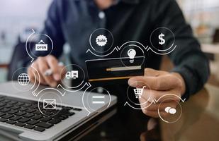 Close up of Hand using credit card and smartphone, laptop computer on wooden desk with VR icon chart graph diagram photo