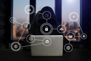 Hacker using computer with digital interface while sitting at desk of blurry interior. Hacking and thief concept. photo