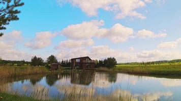 cabaña de madera casa de vacaciones lapso de tiempo estático con nubes pasajeras y reflejos en waterext video