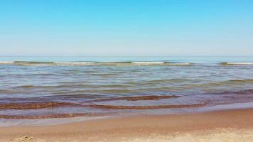 visão estática quebrando pequenas ondas de água clara do mar Báltico calmo em um dia claro de verão sem pessoas nadando. férias de férias na praia da lituânia. video