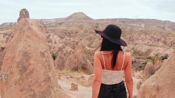 mujer caucásica turista disfrute de la libertad y viaje de vacaciones al aire libre camine entre chimeneas de hadas en el valle de devrent, capadocia video