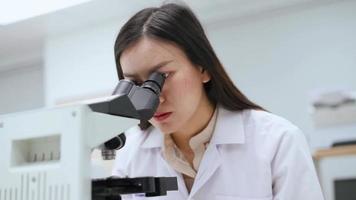 jeune femme scientifique regardant un microscope dans un laboratoire médical video