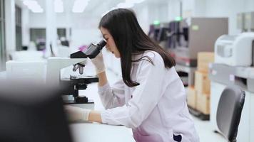 jovem cientista feminina olhando para microscópio em laboratório médico video