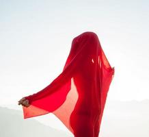 Woman wrapped in a red scarf in the wind photo