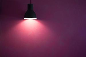 Red wall illuminated by vintage black stylish cone lamp