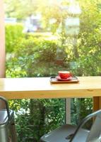 Wooden counter bar and black chairs near the window glass in cafe with coffee in red cup