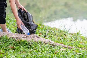 una mujer limpia recogiendo botellas de plástico en un depósito de agua natural. concepto de protección del medio ambiente, salvar el mundo, reciclar, reducir el calentamiento global. primer plano, fondo borroso foto