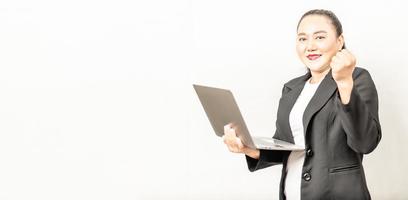 spot focus businesswoman smiling and looking at camera holding a laptop computer, standing and handful, isolated on white background, close-up, copy space left, business, technology photo