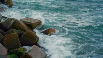 blått klart havsvatten på kusten som bryter över stenar video