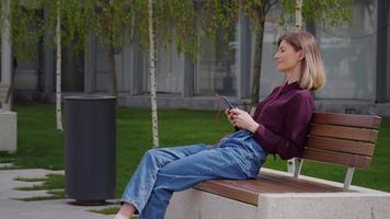 mulher sentada em um banco usando fones de ouvido para ouvir música. video