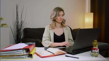 femme gestionnaire prenant des notes d'affaires sur un ordinateur portable, travaillant seule au bureau.