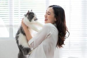 Young Asian woman playing with cat at home photo