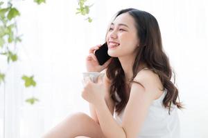 Young Asian woman using smartphone at home in the morning photo