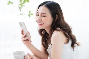 Young Asian woman using smartphone at home in the morning photo