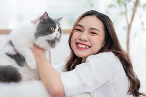 joven asiática jugando con gato en casa foto