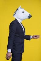 man with horse mask on yellow background photo