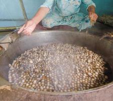 woman untangles the cocoon of the silkworm in the hot cauldron