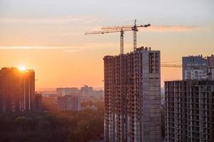 Construction crane building dwelling house at the early morning sunrise time. Kyiv, Ukraine photo